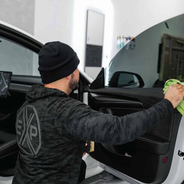 Tesla car window tinting service in USA A TintBusiness employee tinting a Tesla front window in USA